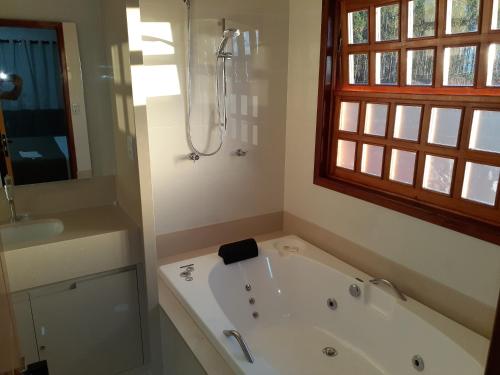 a white bath tub in a bathroom with a window at Hotel e Restaurante Sabor de Minas in Salinas