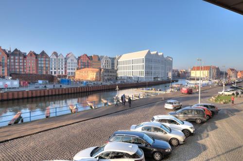 a row of cars parked on a street next to a river at 3 City Apartments - Waterlane Valhalla in Gdańsk