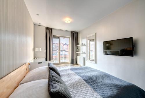 a bedroom with a bed and a flat screen tv at 3 City Apartments - Waterlane Valhalla in Gdańsk