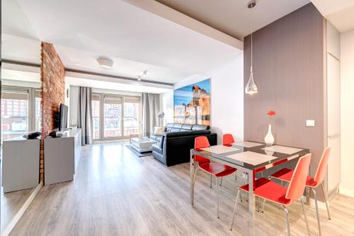 a dining room and living room with a table and chairs at 3 City Apartments - Waterlane Valhalla in Gdańsk
