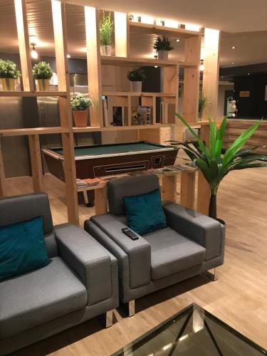 a living room with two chairs and a pool table at Euro Hôtel Airport Orly Rungis in Fresnes