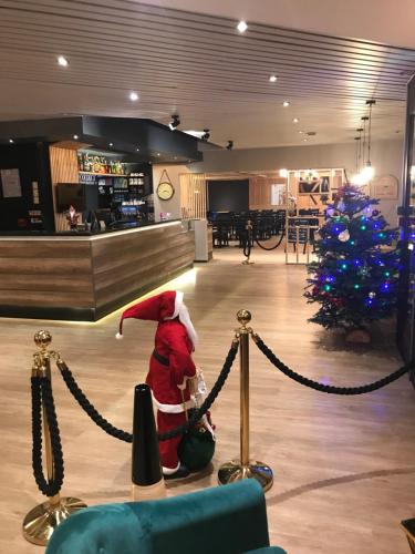 a santa claus standing in front of a christmas tree at Euro Hôtel Airport Orly Rungis in Fresnes