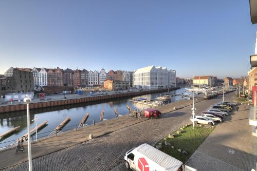 a city with cars parked next to a river at 3 City Apartments - Waterlane Valhalla in Gdańsk