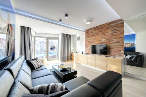 a living room with a couch and a brick wall at 3 City Apartments - Waterlane Valhalla in Gdańsk