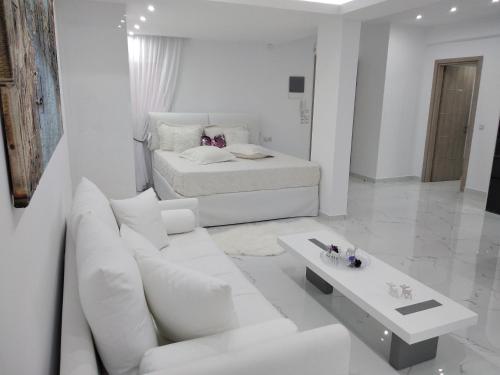 ein weißes Wohnzimmer mit einem Sofa und einem Bett in der Unterkunft Despina's Lux apt Downtown in Iraklio