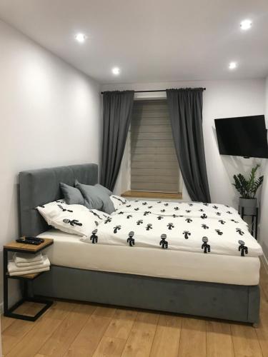 a bedroom with a bed with black and white sheets at Apartament Przy Promenadzie in Jelenia Góra