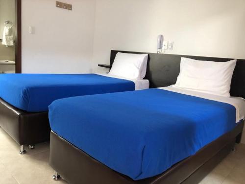 two beds sitting next to each other in a room at Hotel Abadias De Zapatoca in Zapatoca