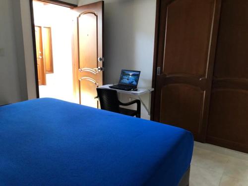 a bedroom with a blue bed and a laptop on a desk at Hotel Abadias De Zapatoca in Zapatoca