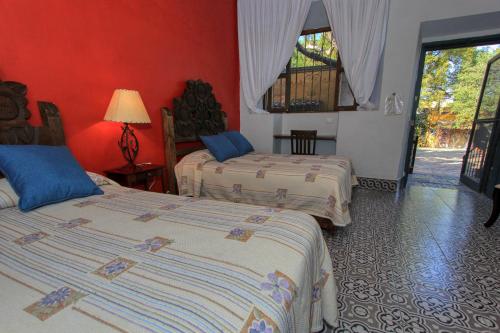 two beds in a room with red walls at Hotel Sautto in San Miguel de Allende