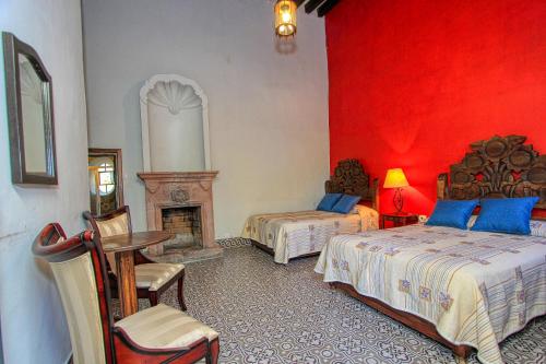 a red bedroom with two beds and a fireplace at Hotel Sautto in San Miguel de Allende