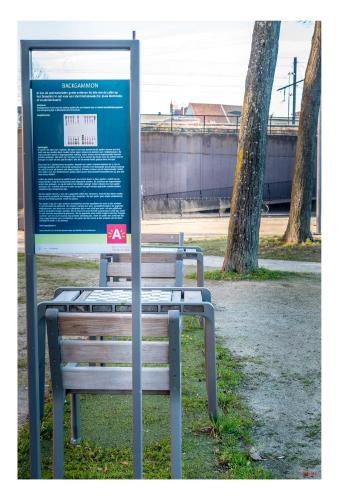 a bench sitting next to a sign in a park at Central Perk Apartments-Antwerp in Antwerp