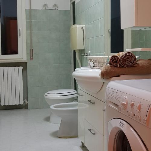 a bathroom with a toilet and a sink and a washing machine at Sweet Home in Falconara Marittima
