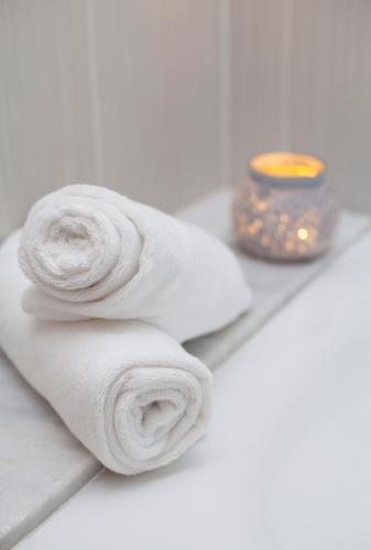 a pile of white towels next to a candle at Benestar In Jalon Valley in Alcalalí