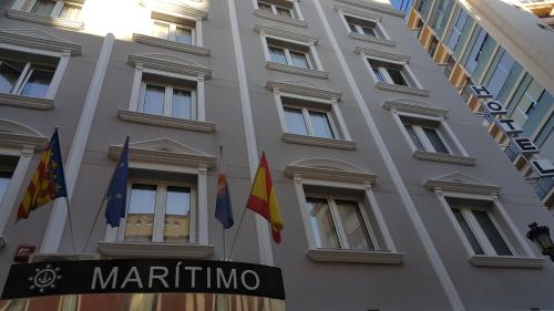 a white building with flags in front of it at Hotel Marítimo Urban in Alicante