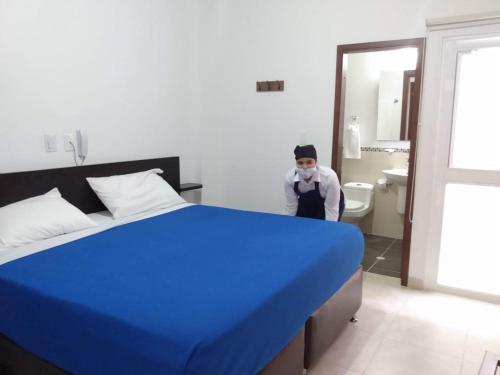a person standing next to a bed in a bathroom at Hotel Abadias De Zapatoca in Zapatoca