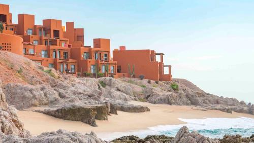 a building on a hill with a beach and the ocean at Club Regina Los Cabos in San José del Cabo