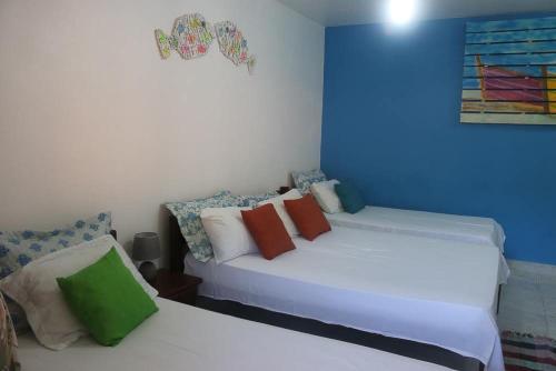 a bedroom with two white beds with colorful pillows at Pousada Piratininga in Niterói