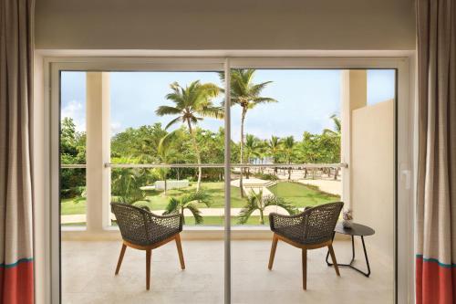 a room with sliding glass doors with a view of a golf course at Secrets La Romana All-Inclusive Adult Only Resort & Spa in Bayahibe