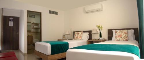 a bedroom with two beds with green and white sheets at Hotel Avanti Chipichape in Cali