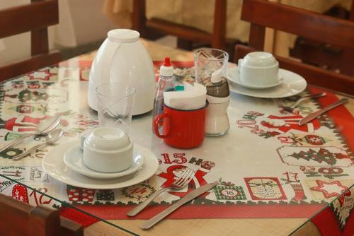 a table with plates and utensils on a christmas table cloth at Pousada Piratininga in Niterói