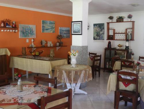 a dining room with tables and chairs and orange walls at Pousada Piratininga in Niterói