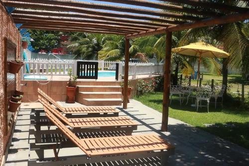 a wooden pergola with benches and an umbrella at Pousada Piratininga in Niterói