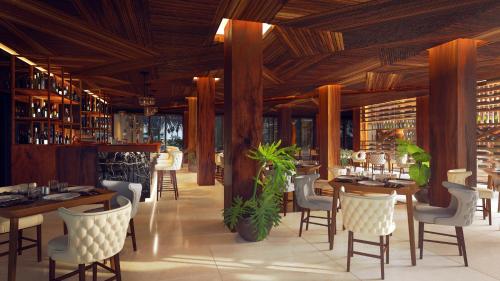 a restaurant with wooden ceilings and tables and chairs at Hotel Beló Isla Mujeres - All Inclusive in Isla Mujeres