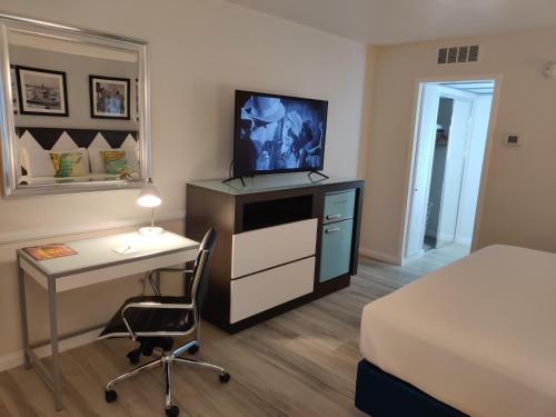a bedroom with a bed and a desk with a television at Kings Inn in San Diego