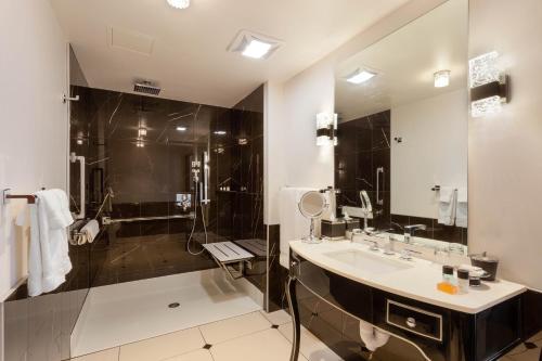 a bathroom with a sink and a shower and a mirror at Hotel Retlaw, Trademark Collection by Wyndham in Fond du Lac