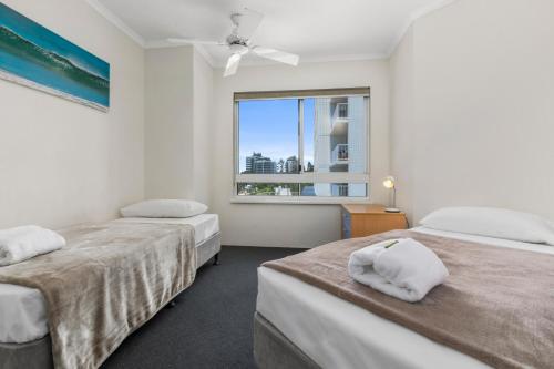 2 camas en una habitación con ventana en The Burlington Holiday Apartments, en Maroochydore