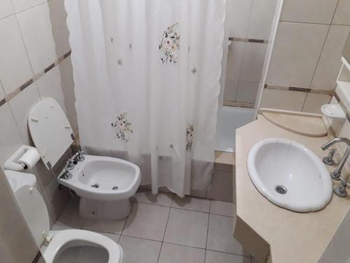 a bathroom with a toilet and a sink and a shower curtain at Habitaciones confortables con baño privado in San Rafael