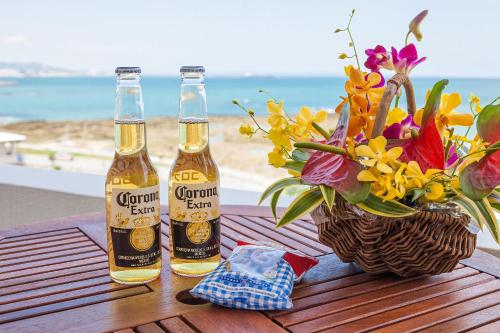 two bottles of beer on a table with a vase of flowers at Yonabaru Hotel SUNRIZE OCEAN in Yonabaru
