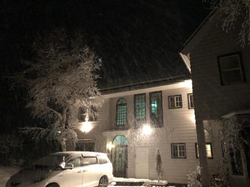 a white car parked in front of a house at night at Vegetarian House Jamoo in Yamanakako