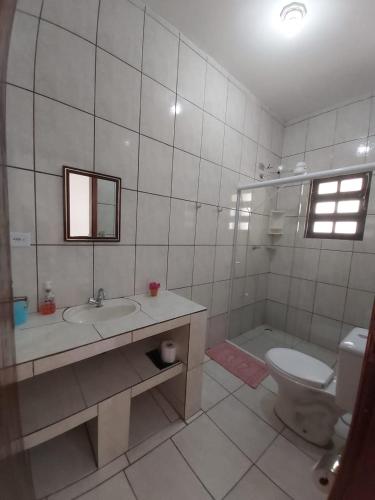 a bathroom with a sink and a toilet and a tub at Maranata Suítes in Peruíbe