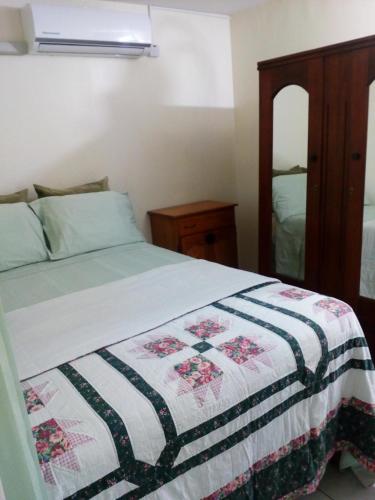 a bedroom with a bed with a quilt on it at Cozy & Comfy in Portmore