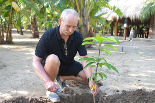 an older man planting a plant in the sand at Agro Village Resort , Kalpitiya in Kalpitiya