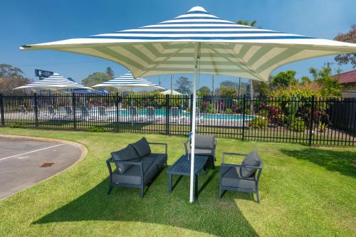 two chairs and an umbrella on the grass at Hotel Forster in Forster