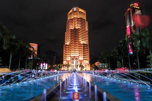 um edifício alto com uma fonte em frente em EXPRESSIONZ KLCC BY G Suites em Kuala Lumpur