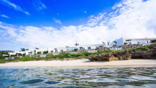 宮古島にあるクリスタルヴィラ宮古島砂山ビーチの家屋と水辺のあるビーチの景色を望めます。