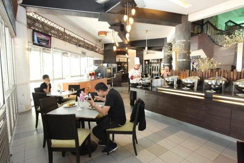 a man sitting at a table in a restaurant at GloRy BeAch ResOrt private apartment in Port Dickson