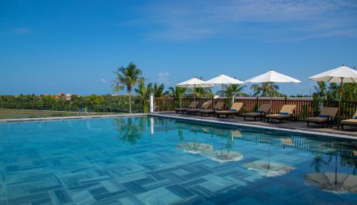 Legacy Hoi An Resort في هوي ان: مسبح مع كراسي ومظلات
