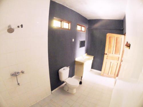 uma casa de banho com um WC, um chuveiro e uma porta em East Lombok Dive Hotel - 3 private rooms on the beach with seaview & scuba diving center em Labuhan Pandan