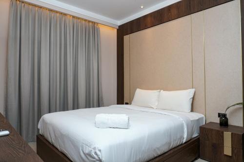ジャカルタにあるMinimalist and Cozy 2BR Citralake Suites Apartment By Travelioの白いシーツが敷かれた大きなベッドのある寝室