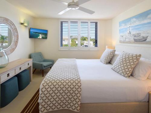 a bedroom with a white bed and a blue chair at Fairshore Noosa in Noosa Heads