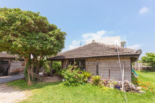 a small house in a yard with a tree at Uminchuno Yado in Nago