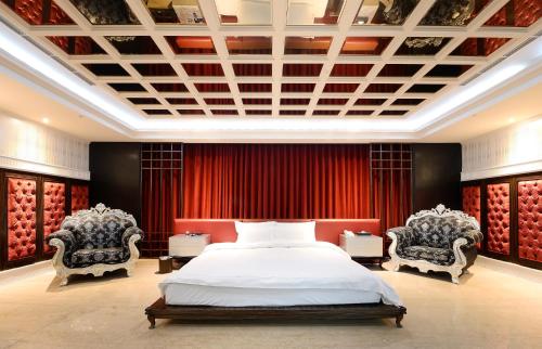 a bedroom with a large bed and two chairs at OHYA Chain Boutique Motel-Linkou in Linkou