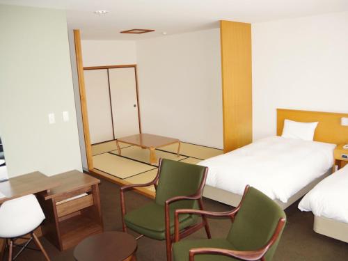a bedroom with a bed and two chairs and a table at Hotel Familio Tateyama in Tateyama