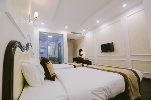 a hotel room with two beds and a television at Vincent Halong Hotel in Ha Long