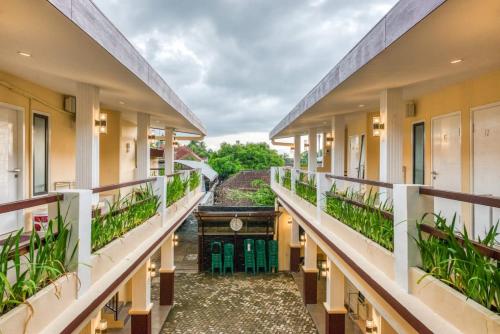 a corridor of a building with green plants at RedDoorz Syariah near Kebon Rojo Park Blitar in Karangtengah