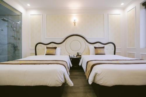 a hotel room with two beds and a shower at Vincent Halong Hotel in Ha Long